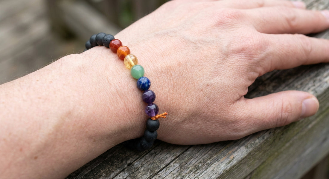 A close‑up of a hand wearing a handcrafted Shungite chakra bracelet, natural stone beads glinting against skin, soft daylight, realistic style, alt="hand wearing shungite chakra bracelet"