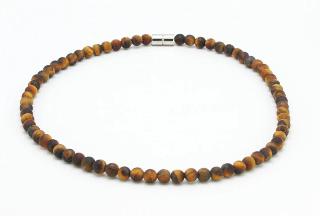 A realistic close‑up of a beaded tiger eye necklace lying on a wooden table, soft natural light highlighting the golden 