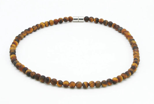 A realistic close‑up of a beaded tiger eye necklace lying on a wooden table, soft natural light highlighting the golden 