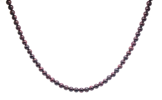 Genuine garnet necklace with deep red gemstone beads, glowing softly in natural light