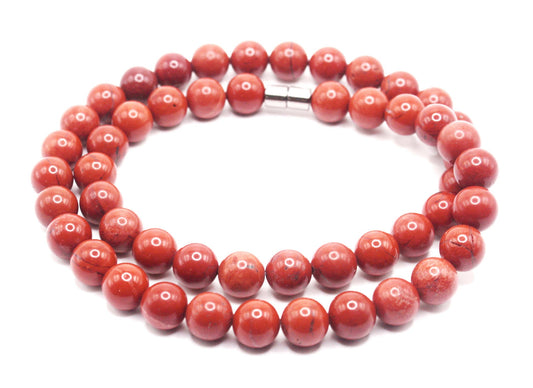 Polished red jasper gemstone necklace with earthy red beads in warm natural light